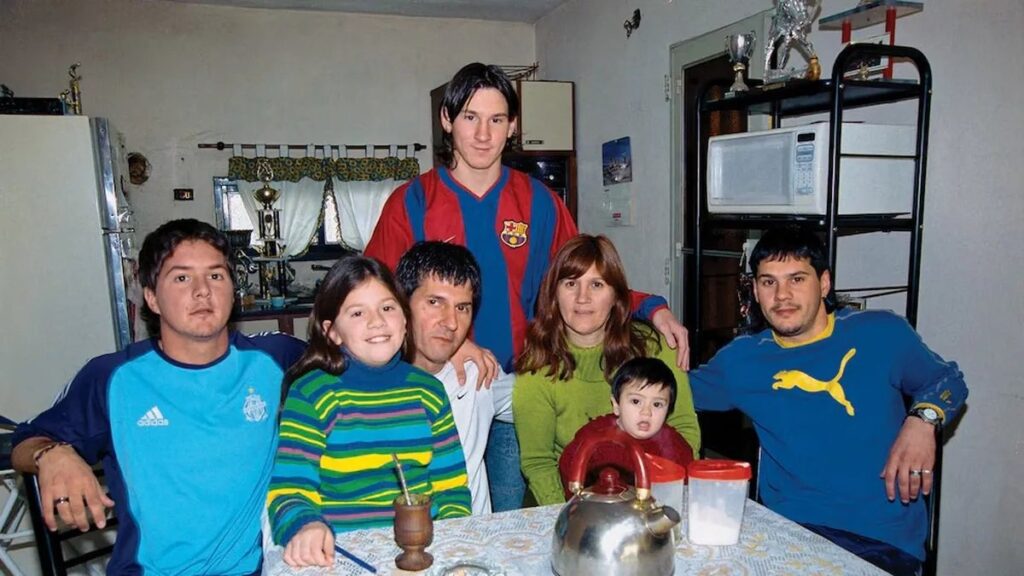 La familia Messi con Lionel utilizando la camiseta del Barcelona y Jorge (de blanco) sentado en el centro de la mesa.